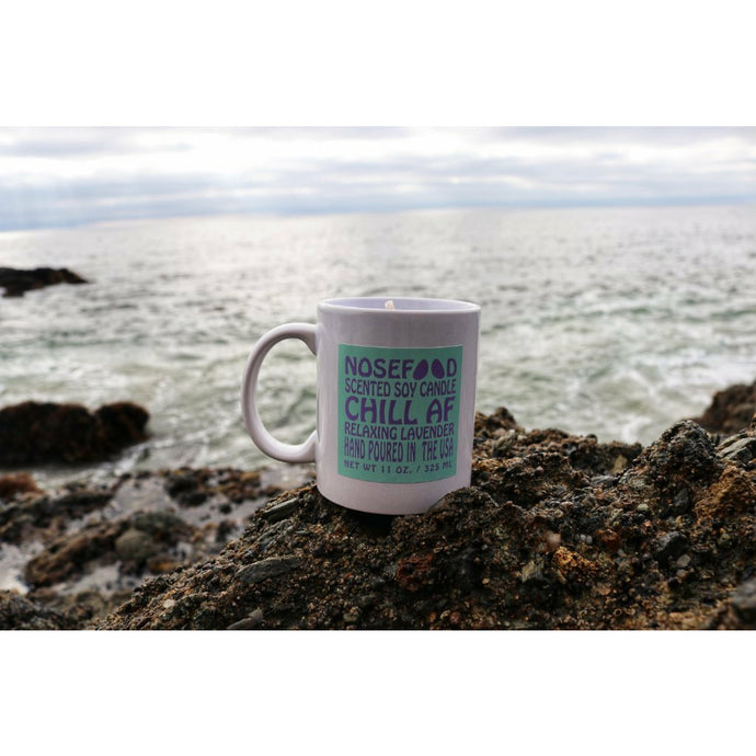 NoseFood brand Chill AF Lavender candle in white mug on rock by ocean
